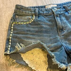 Free People distressed denim shorts with green and white trim. Size 26